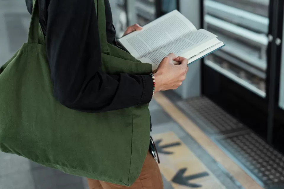 Close-up of person standing and holding book on train platform.